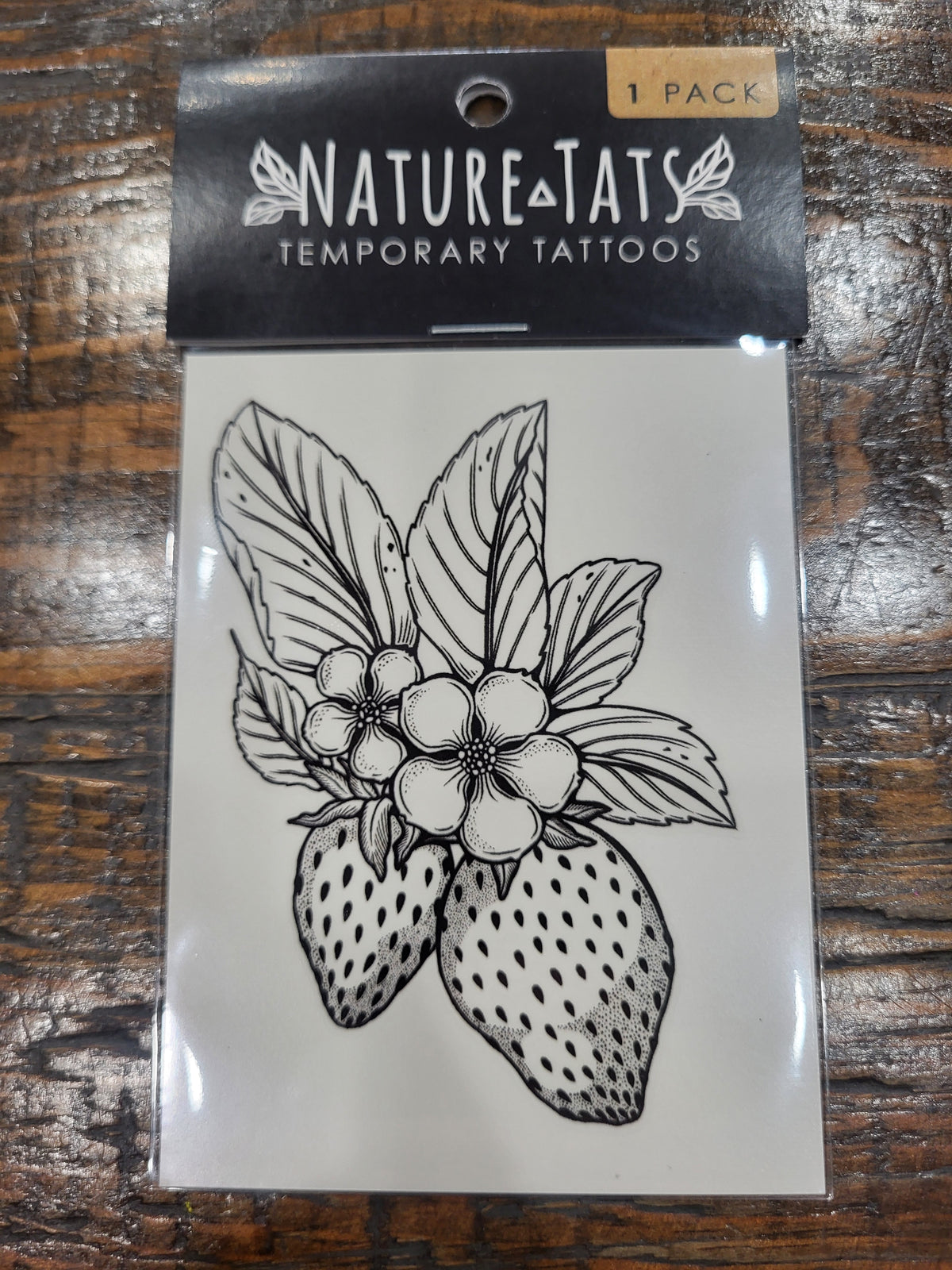 Temporary NatureTats tattoo sheet with black strawberry flower outline on white backing