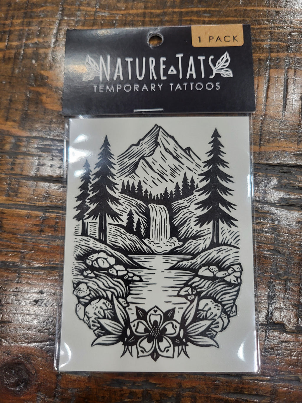 Temporary tattoo sheet with black mountain landscape, trees, rocks, and flowers