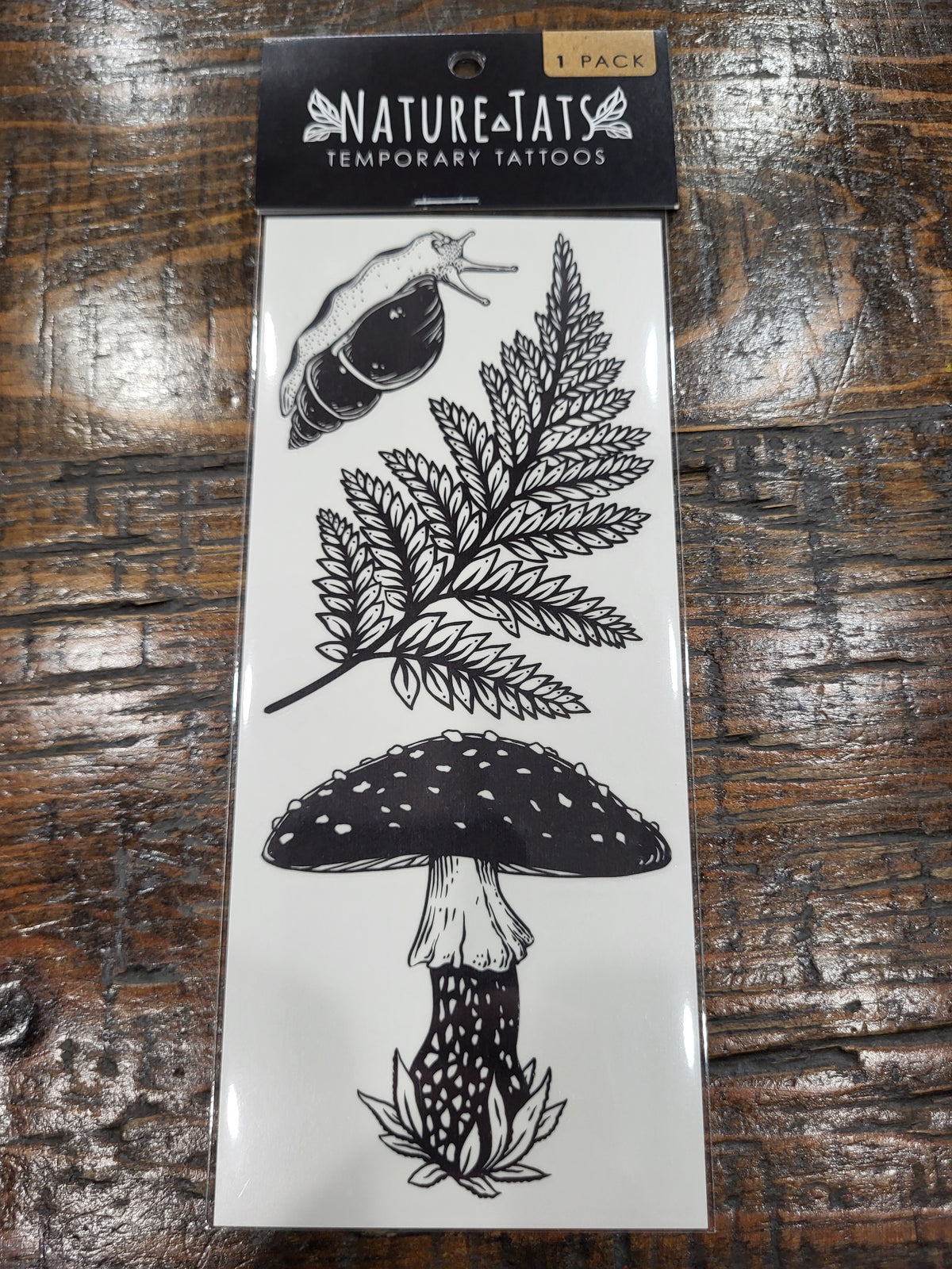 Temporary tattoo sheet pack with black fern, mushroom and snail illustrations.