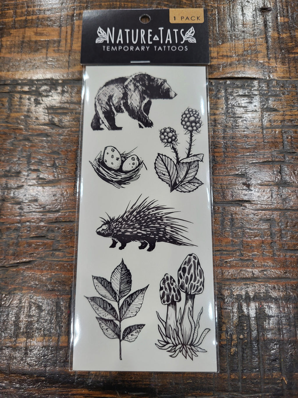 Temporary tattoo sheet showing a black bear, hedgehog, leaves and flowers