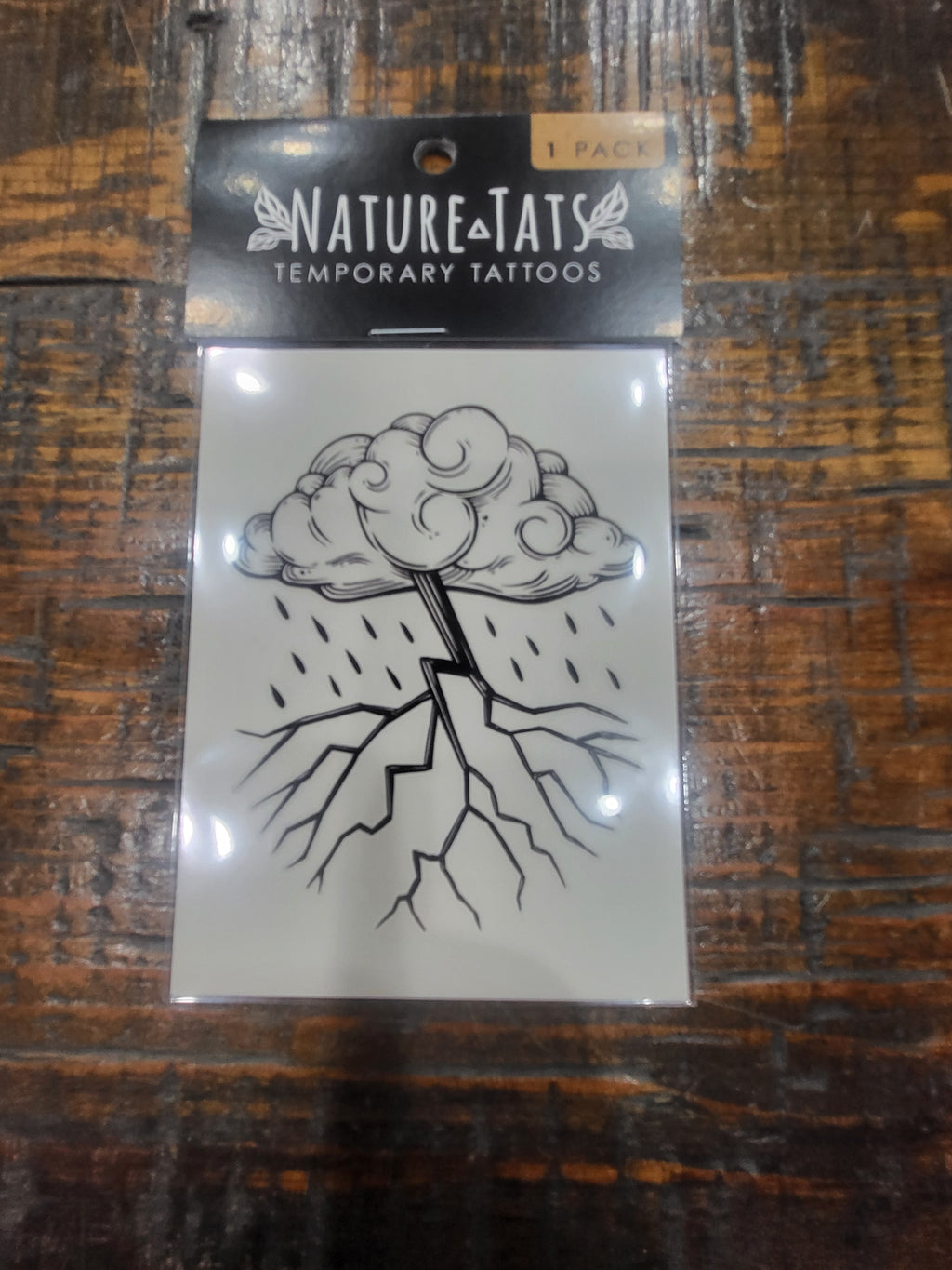 Storm cloud temporary tattoo sheet in package with black line-drawn cloud and lightning