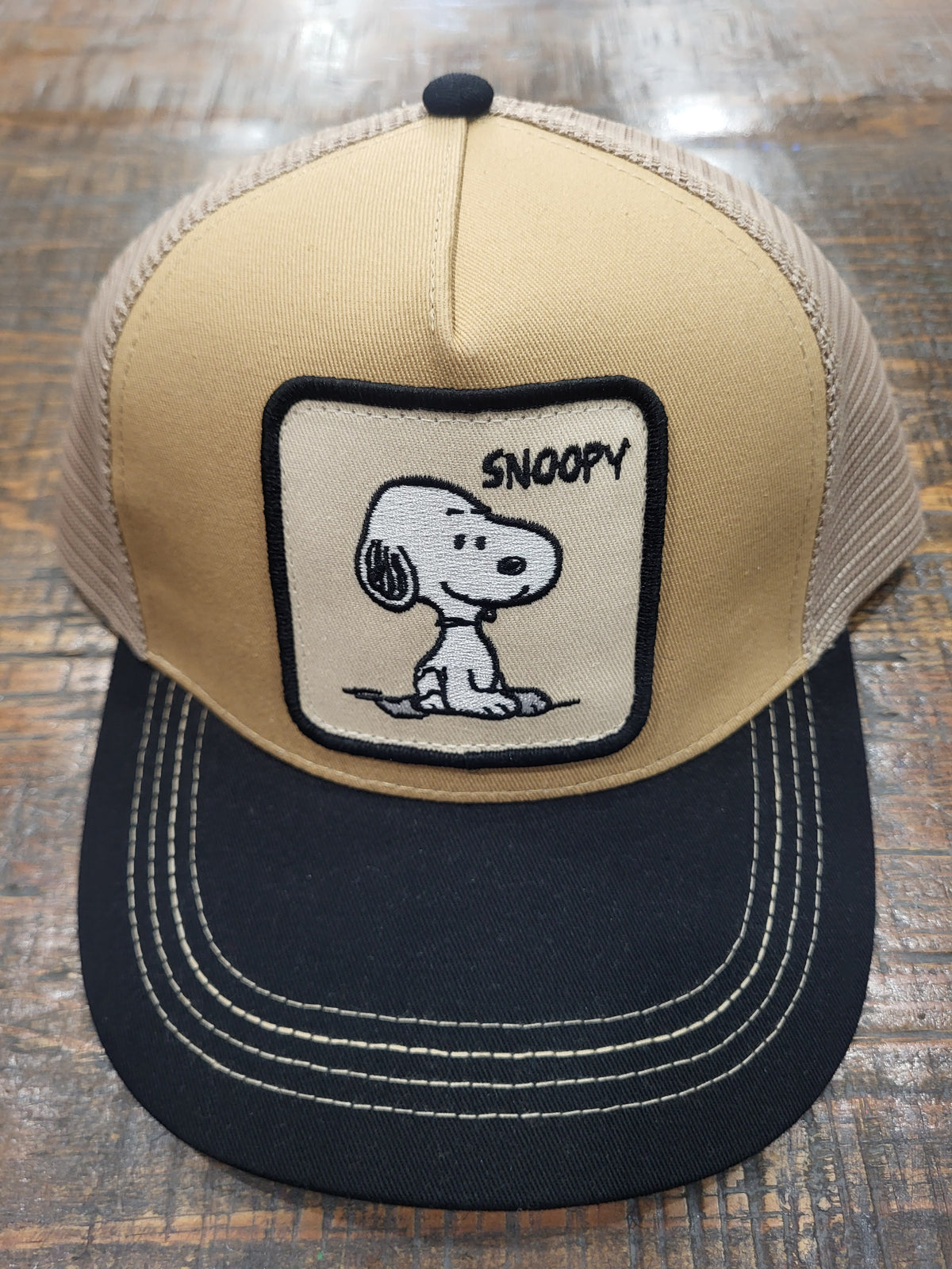 Beige and dark trucker hat with mesh back and Snoopy character front patch