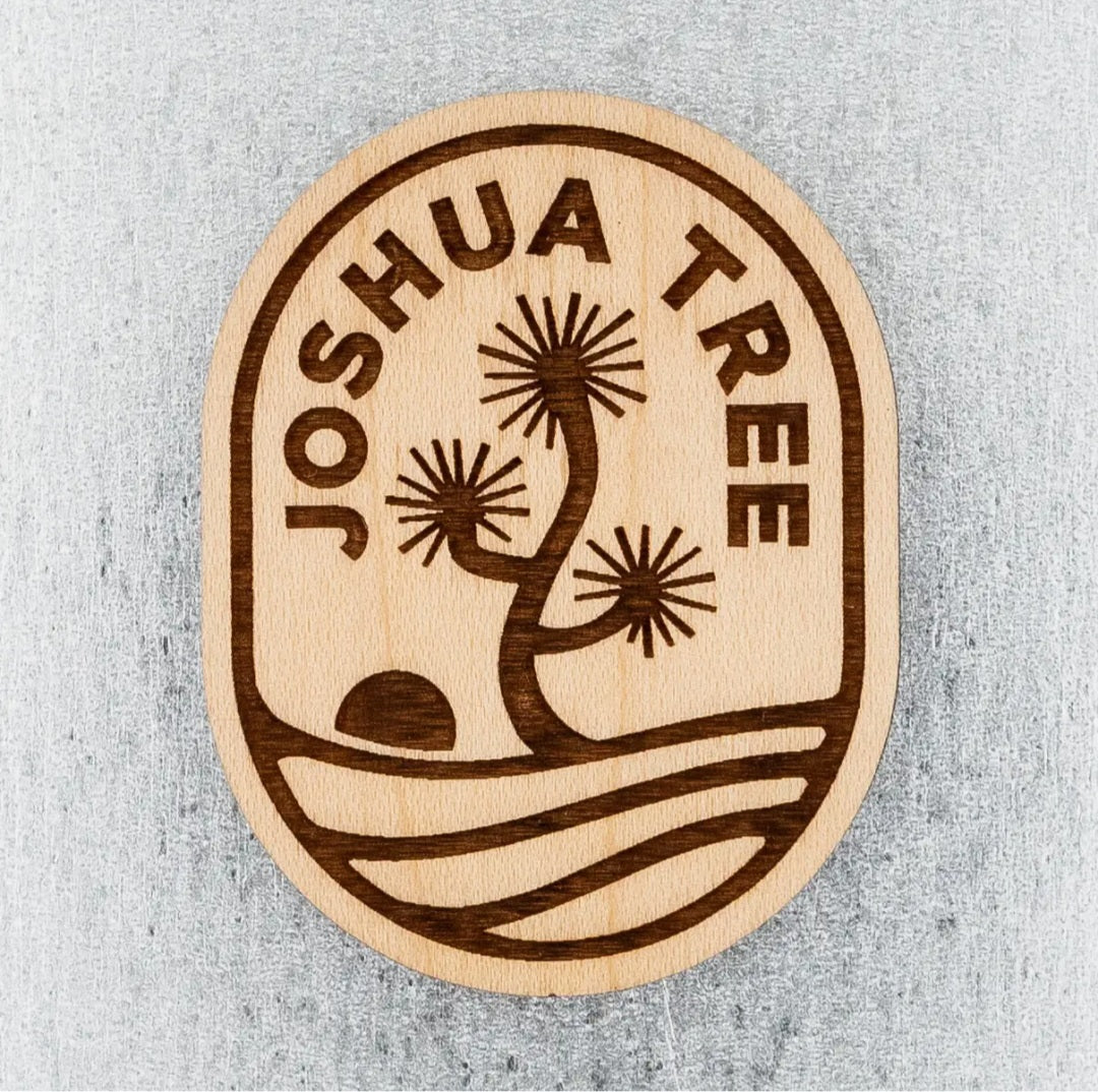 Oval wooden magnet with Joshua Tree lettering and desert sunburst design