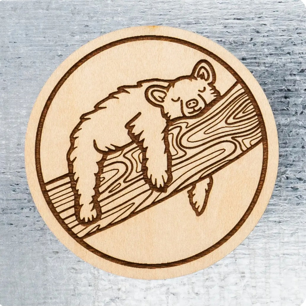 Circular wood magnet with sleeping bear illustration and wood-grain border