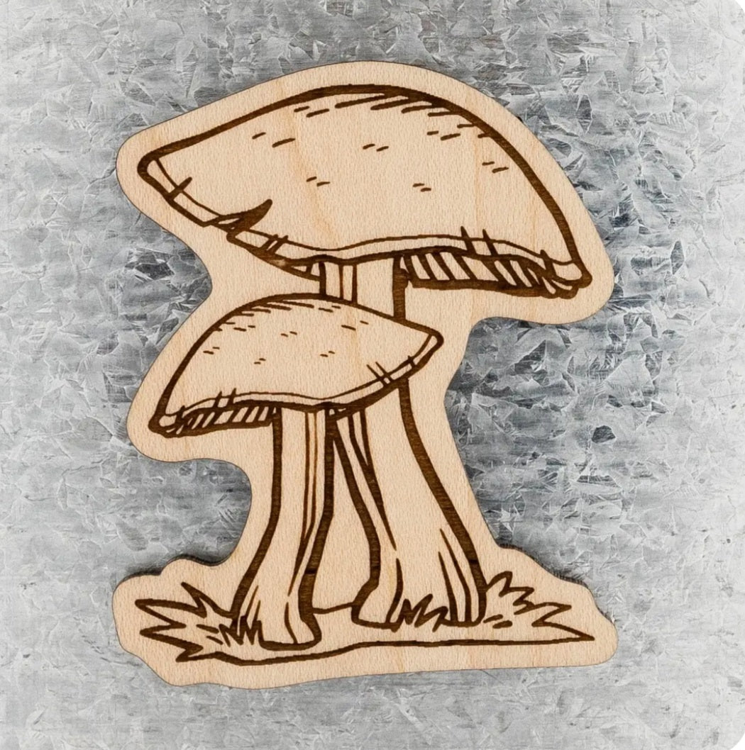 Wooden mushroom magnet with beige cap and stem cutout on light wood backing