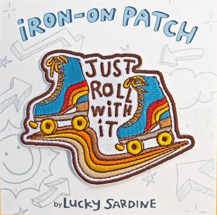 Iron-on roller skate patch with blue skates and text 'JUST ROLL WITH IT'