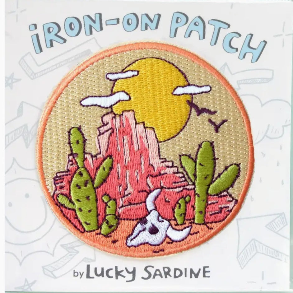 Iron-on patch with circular desert scene, yellow sun, cacti, and mountains