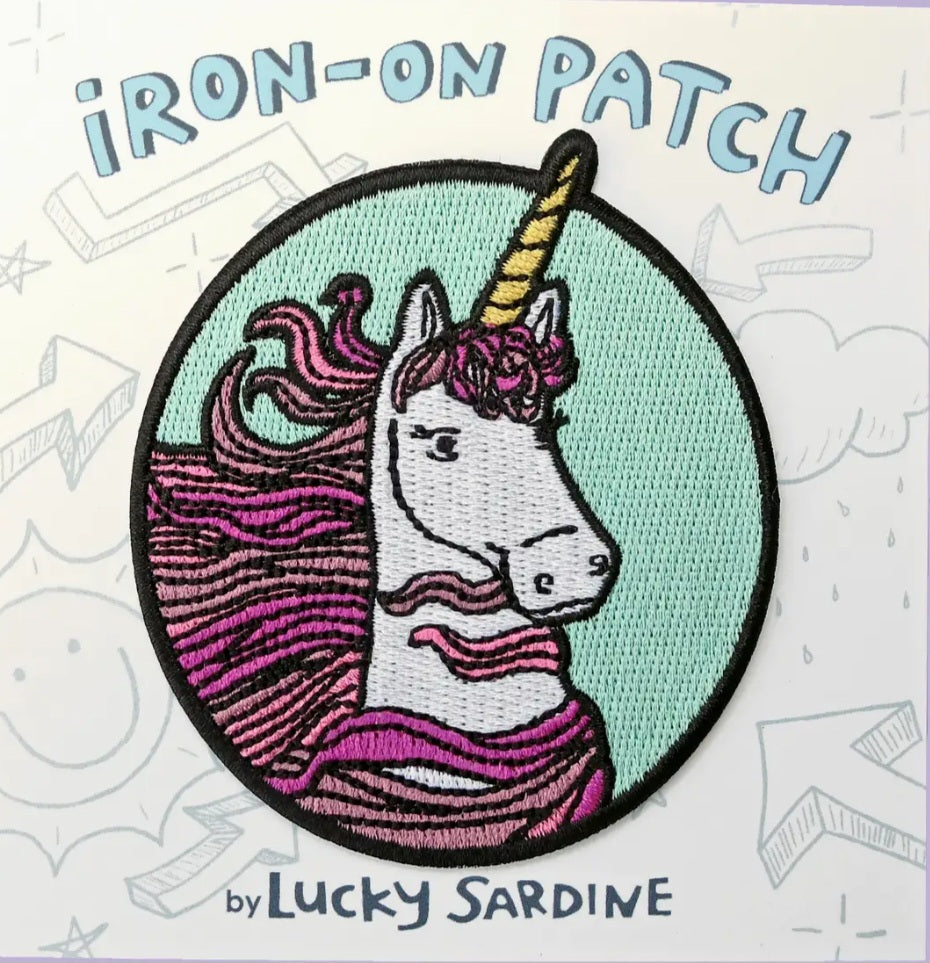 Round unicorn iron-on patch with teal background and purple striped mane, black border