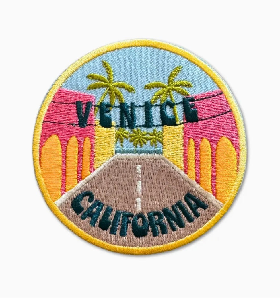 Round embroidered iron-on patch with Venice and California text, palm trees and skyline.