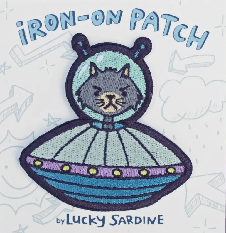Embroidered iron-on patch with cat in purple-and-blue alien spaceship, stitched details