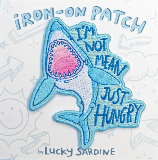 Blue shark iron-on patch with stitched border and text "JUST HUNGRY"