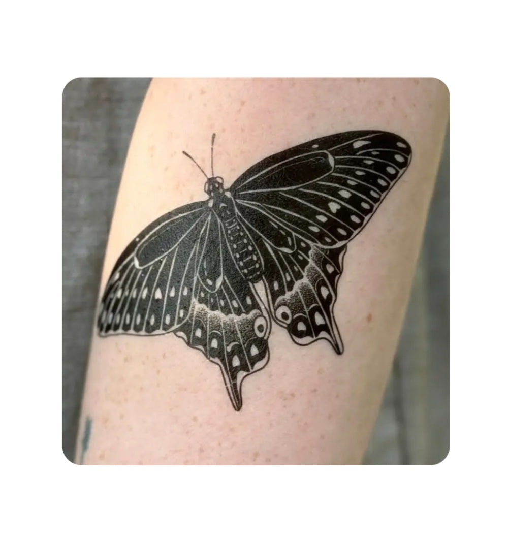 Black swallowtail butterfly temporary tattoo on skin, black ink with white highlights