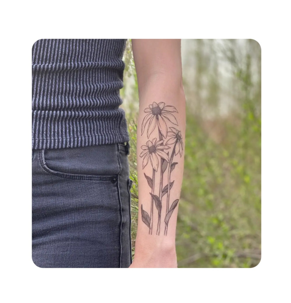 Temporary coneflower tattoo on forearm with thin black and pink floral outlines