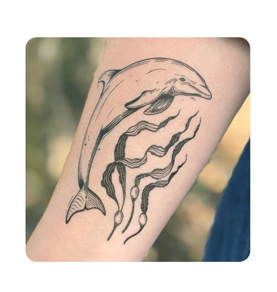 Dolphin temporary tattoo on light skin: black dolphin with wave-like details
