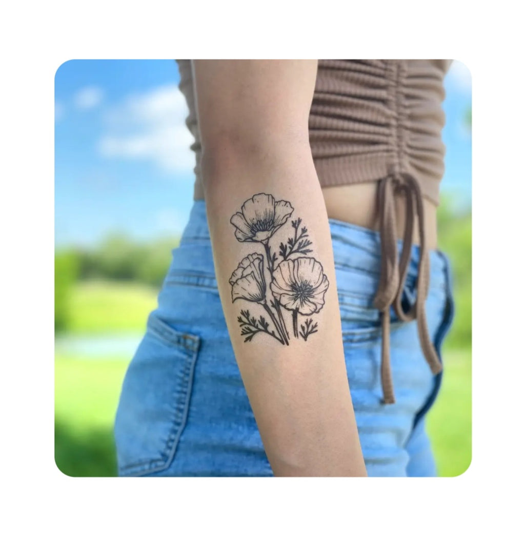 Temporary poppy floral tattoo on forearm, black outline design