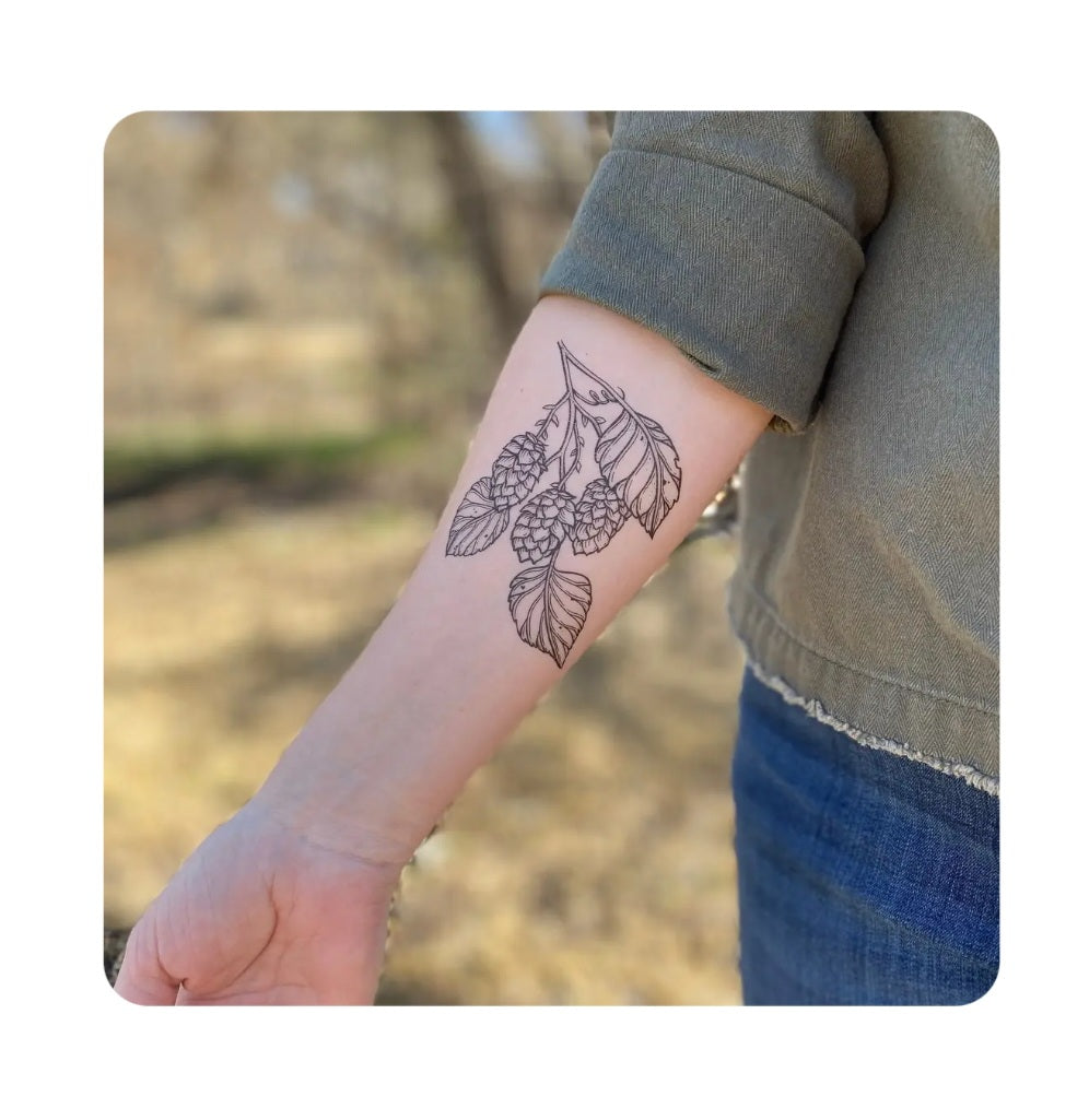 Hops vine temporary tattoo on wrist in black line art, leafy hops cluster