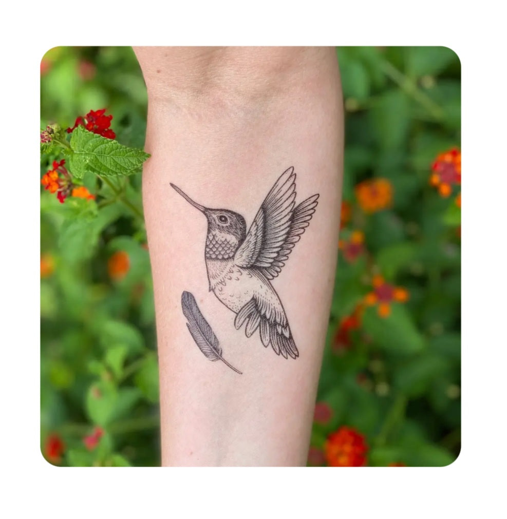Hummingbird temporary tattoo on arm, black line-art bird with wings.