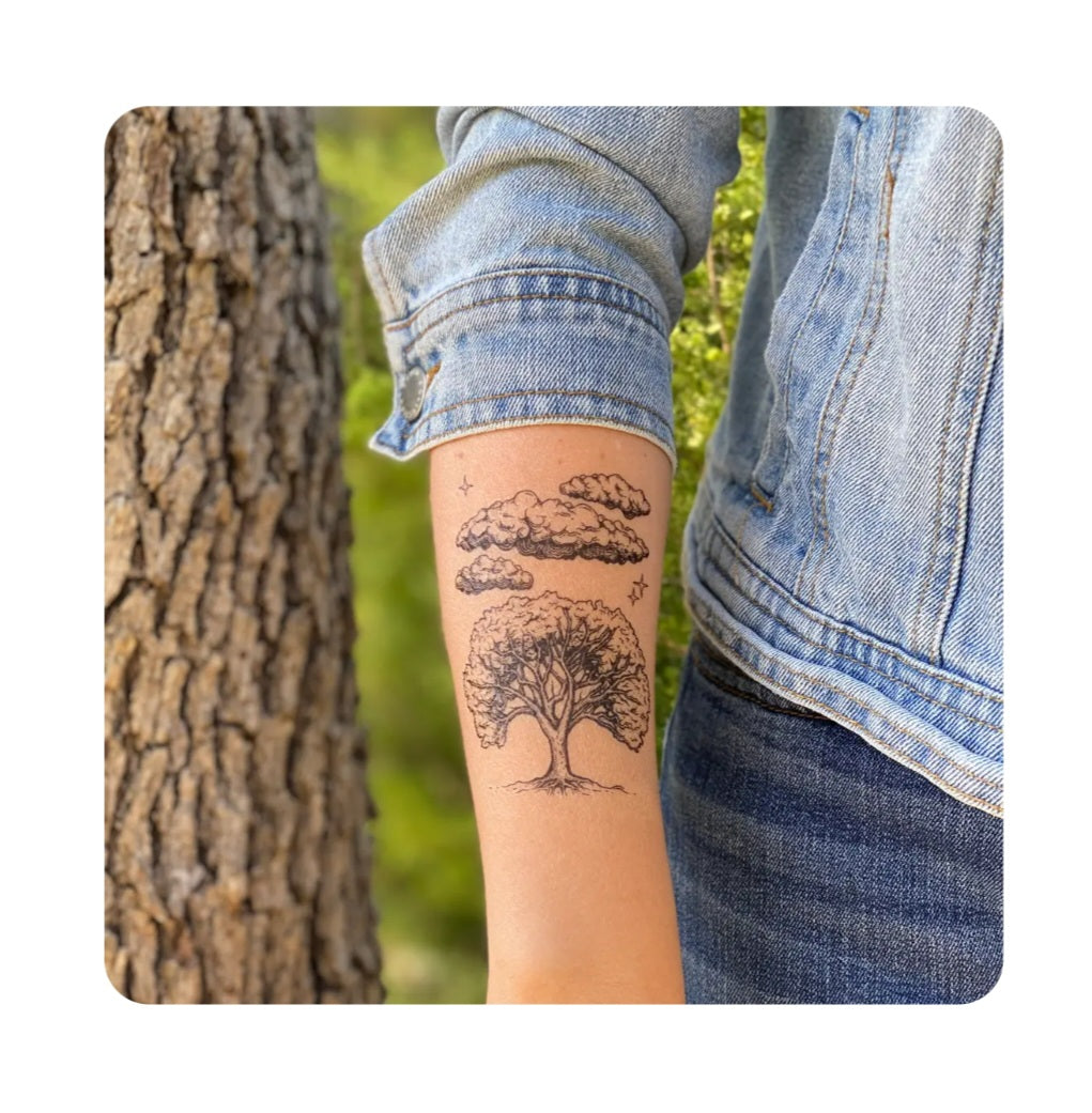 Temporary tattoo of a tree with clouds on a forearm, black ink look