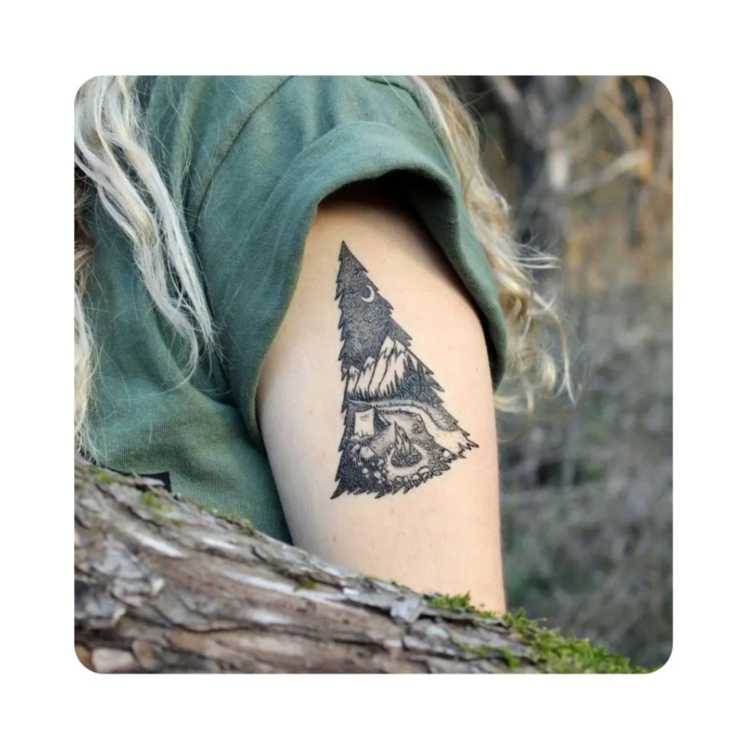 Temporary tattoo of black pine tree campsite on forearm.