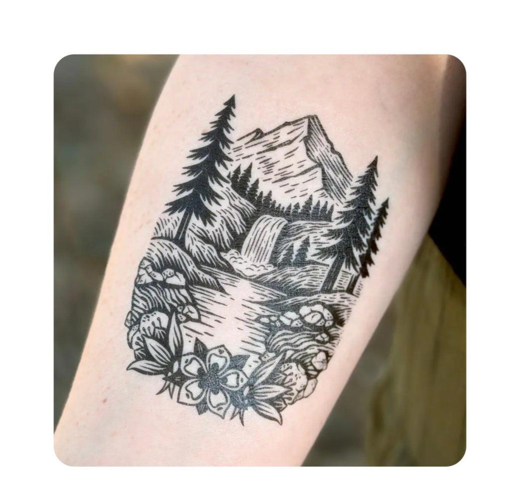 Temporary tattoo with black-and-gray mountain forest scene and floral accents