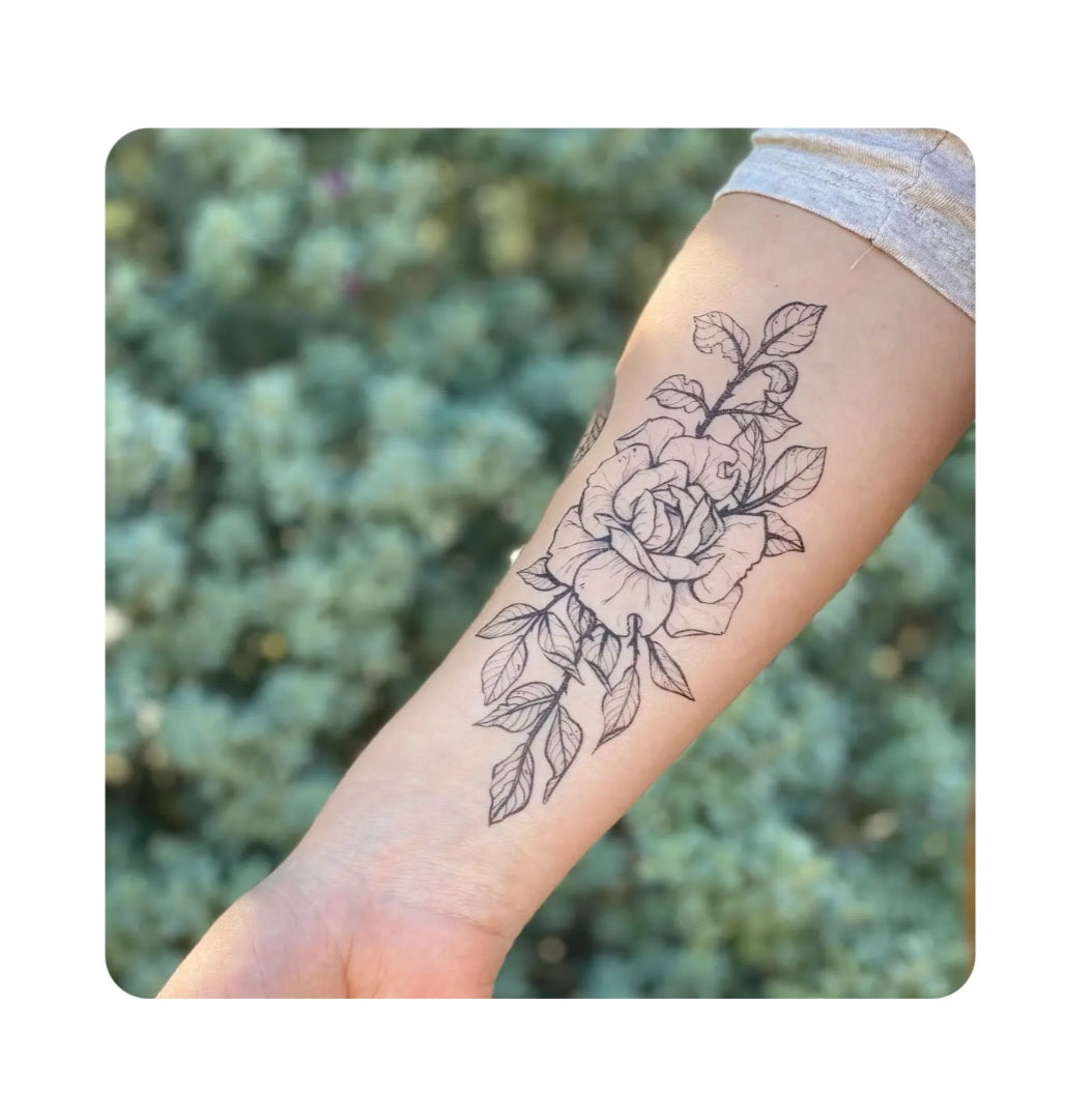 Rose blossom temporary tattoo in black line art on forearm