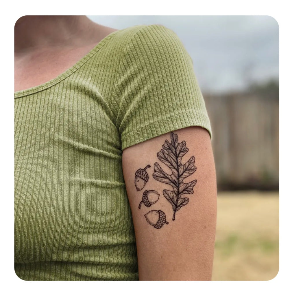 Temporary acorn and oak leaf tattoo on forearm, dark ink outline
