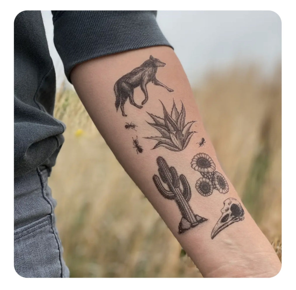 Temporary tattoo on arm with desert animal, cacti, flowers, and insect designs