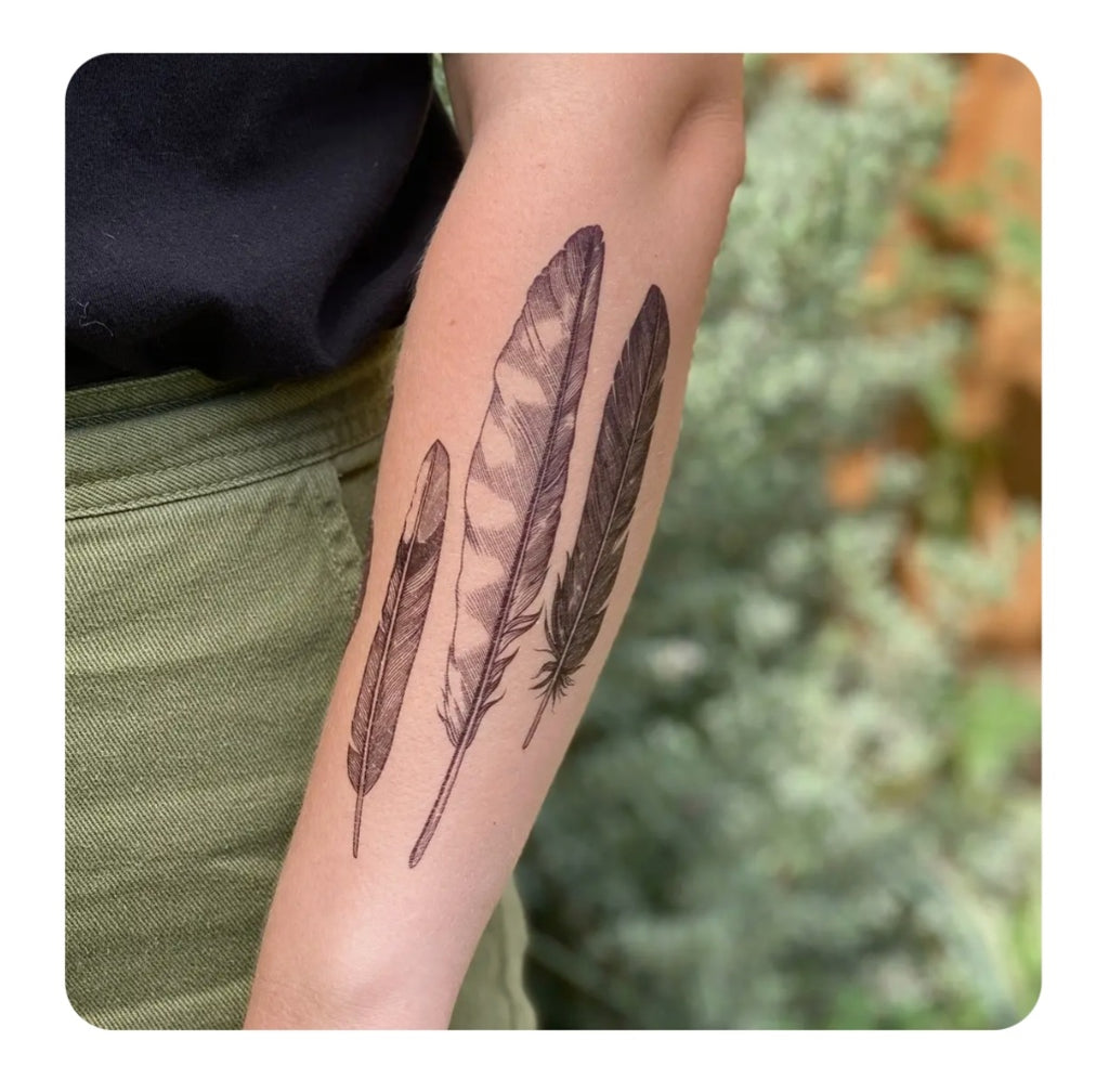 Temporary tattoo with two black feather designs on an arm