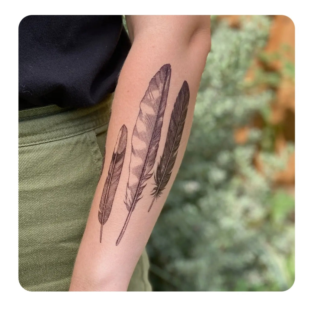 Temporary tattoo with two black feather designs on an arm