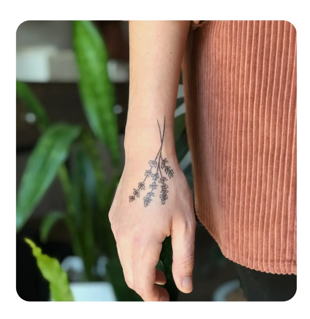 Temporary twig branch tattoo on wrist and hand in dark ink, floral style