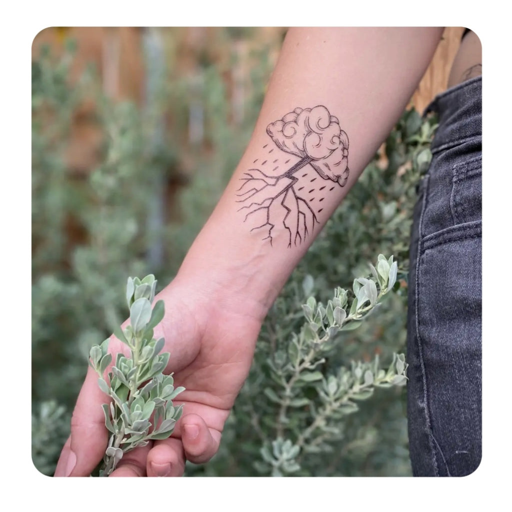 Storm cloud temporary tattoo on bare wrist with line-drawn cloud and rain